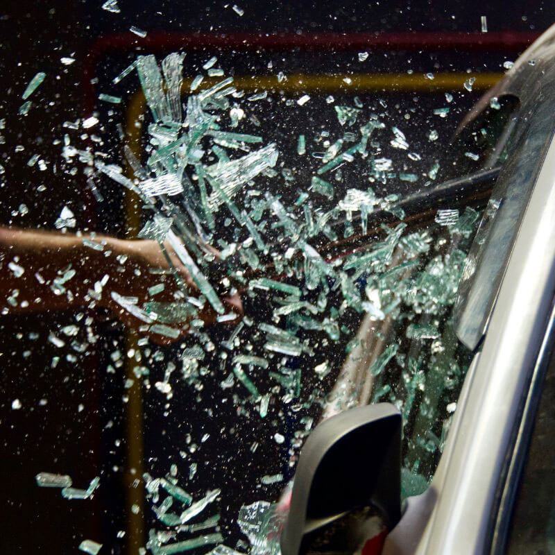 car window getting smashed with a hammer and glass flying out
