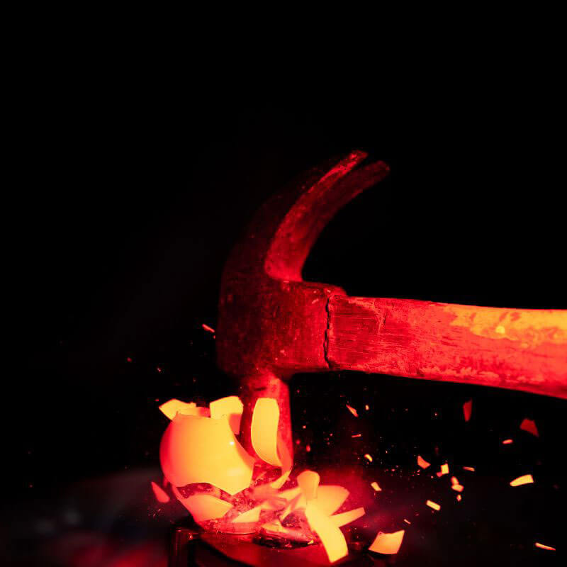 red glowing hammer smashing a lightbulb with a dark black background